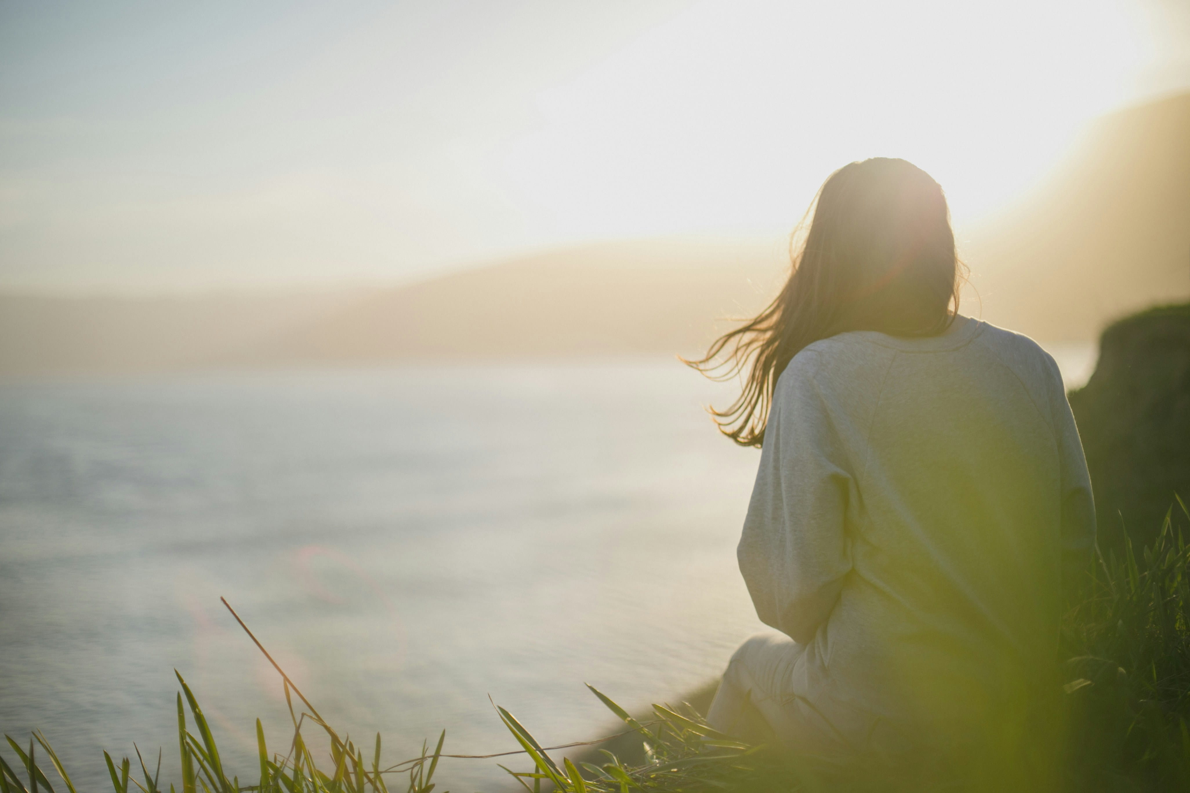 Woman sat looking at a the ocean