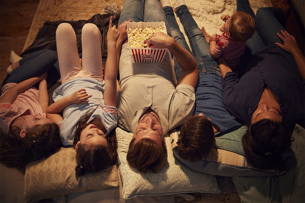Family lying down watching a film together