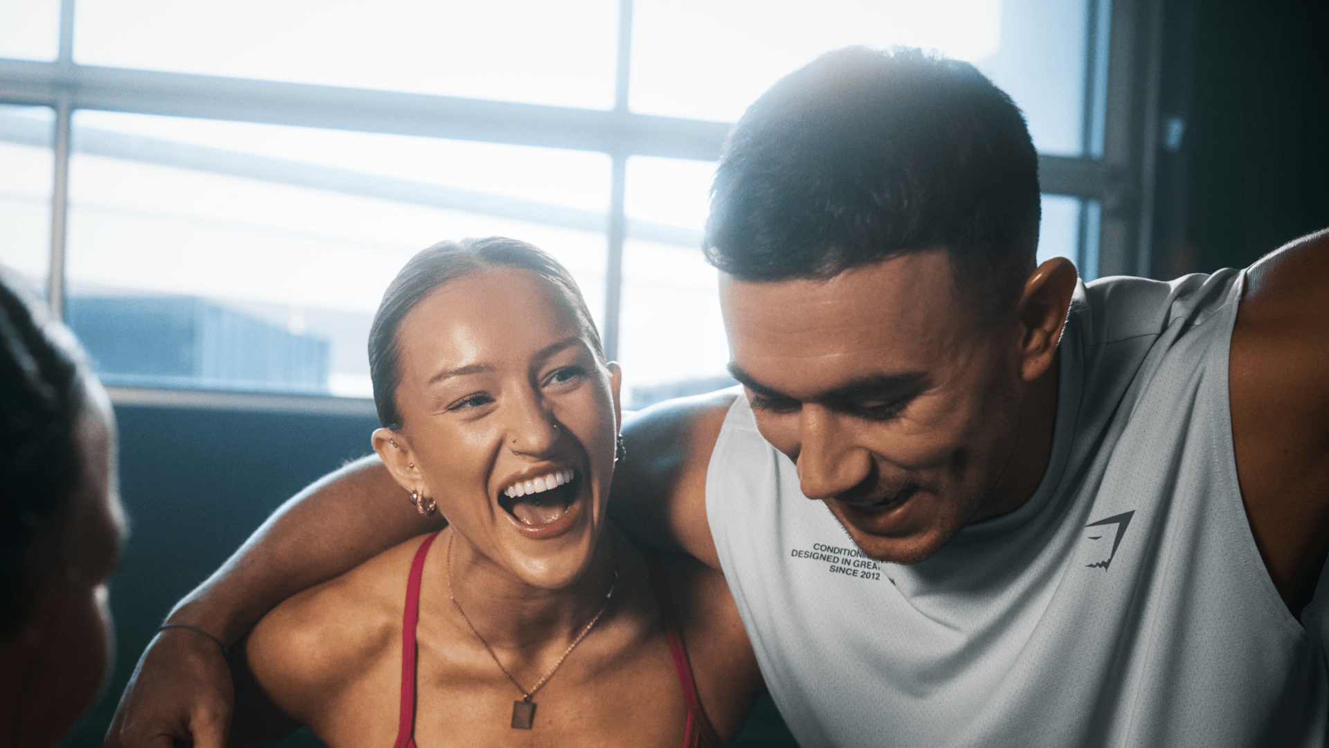 Man and woman smiling at the gym wearing Gymshark branded clothing