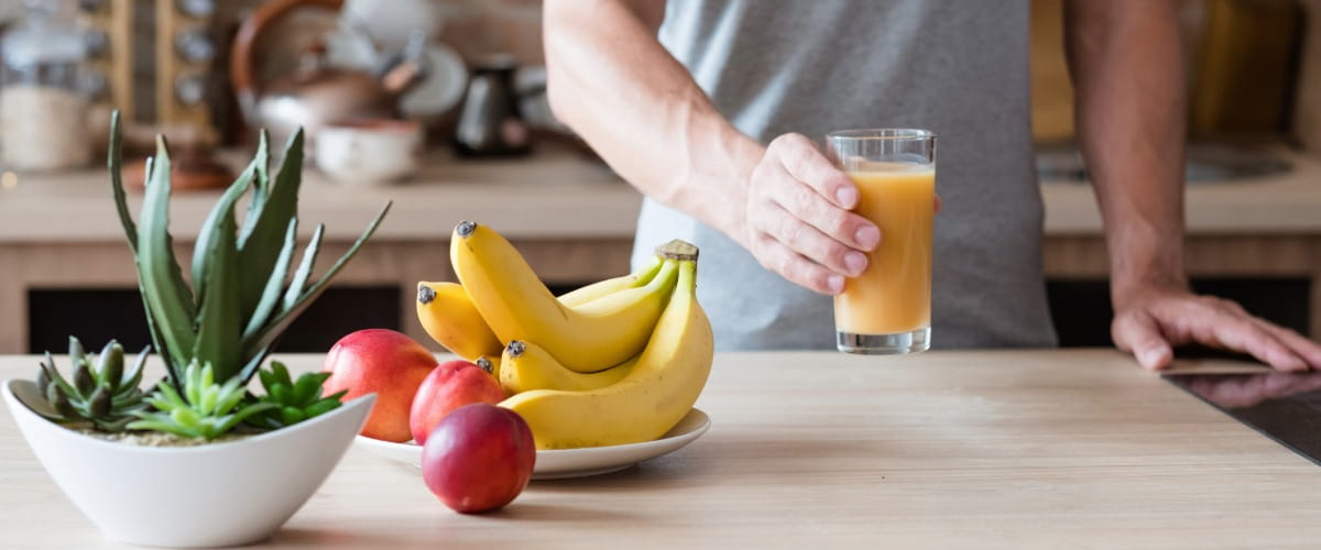 person-holding-glass-of-juice-on-table-with-fruit